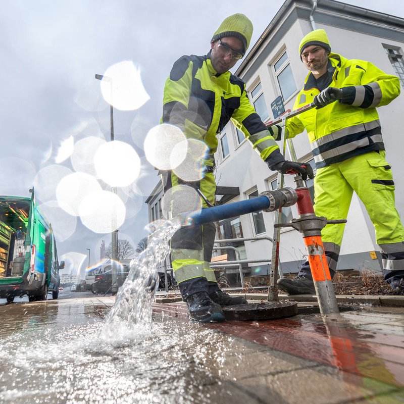 Zwei Männer von Gelsenwasser arbeiten an einem Hydranten im Wasserverteilnetz: Arbeiten im Team blau-grün von Gelsenwasser - aktuelle Stellenangebote und Arbeitskultur
